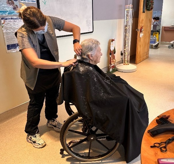 A patient in a wheelchair gets their hair cut.